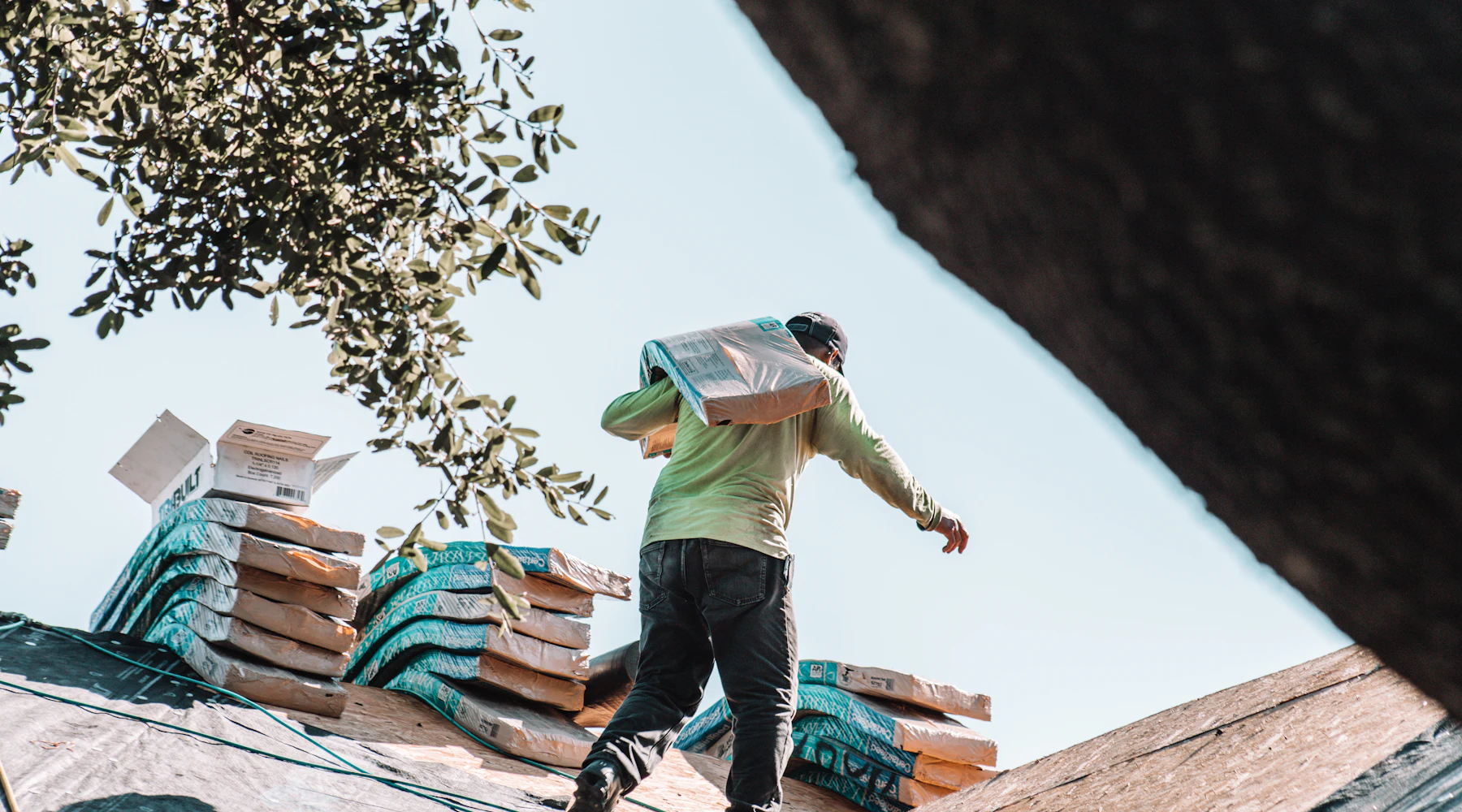 Roofer carrying shingles across a residential roof